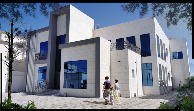 مبنى حديث واجهته مغطاة بالزجاج العاكس، يعكس السماء والمباني المحيطة. | A modern building with a glass façade reflecting the sky and surrounding structures.